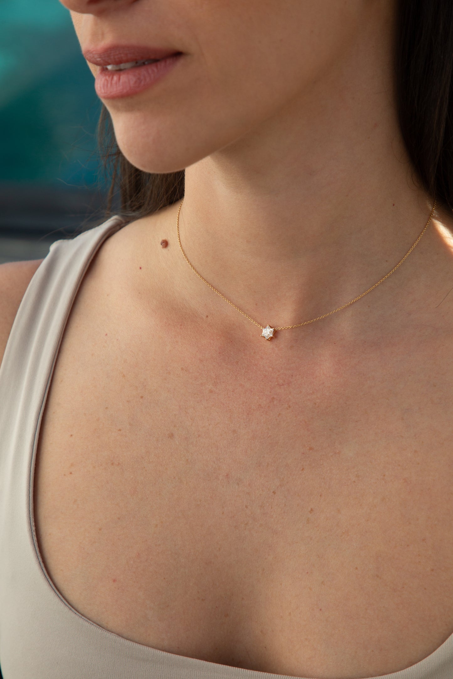 woman wearing a white tank top showcasing a gold necklace